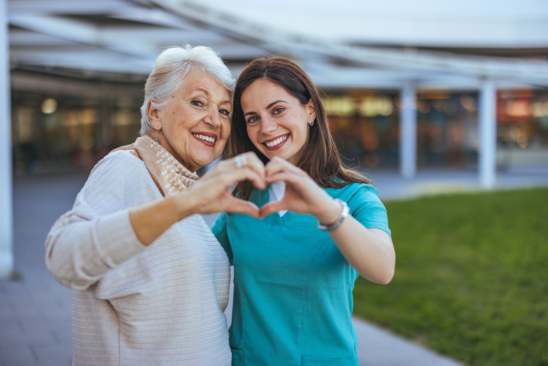 Senior Woman and Caregiver Forming Heart Shape Outdoors